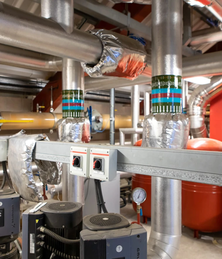 Close-up of interconnected heating system pipes, pumps, and insulated valves used for industrial heating and ventilation. Close-up of interconnected heating system pipes, pumps, and insulated valves used for industrial heating and ventilation.